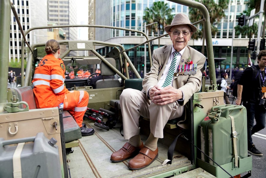 older man in back of jeep wearing a suit and military medals