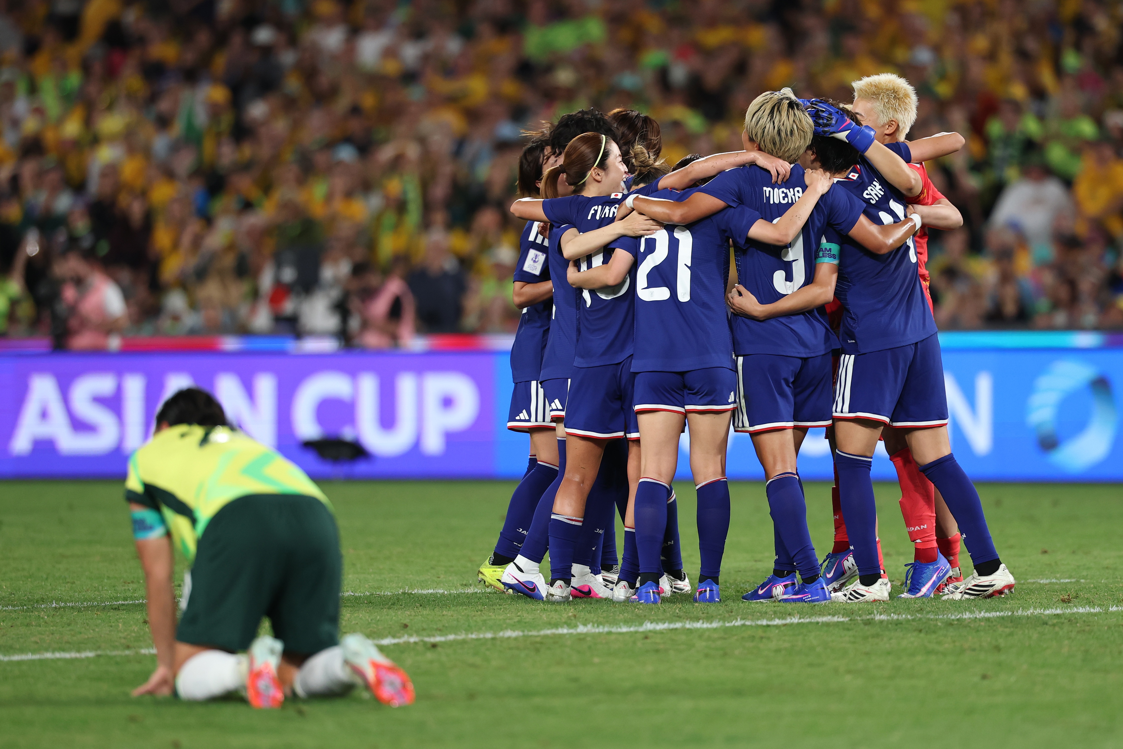 Sam Kerr se inclina na frente dos jogadores japoneses comemorando