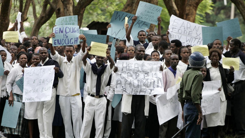 A Zimbabwean riot policeman stands in front of doctors and nurses during demonstration in Harare.