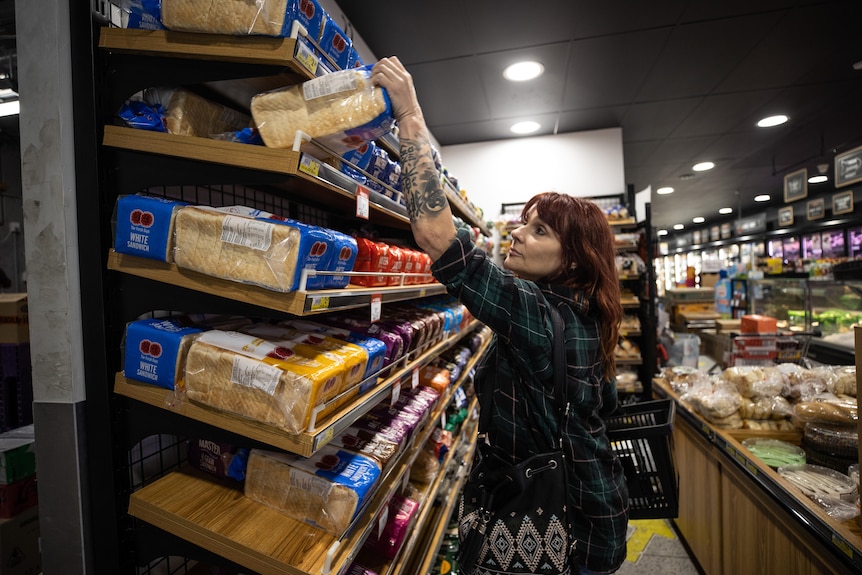 A woman in the supermarket, buying bread.
