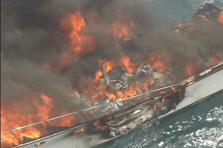 A close up of a boat on fire in the ocean.
