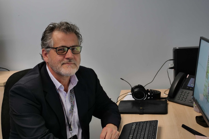 Man wearing glasses and suits sits at a desk