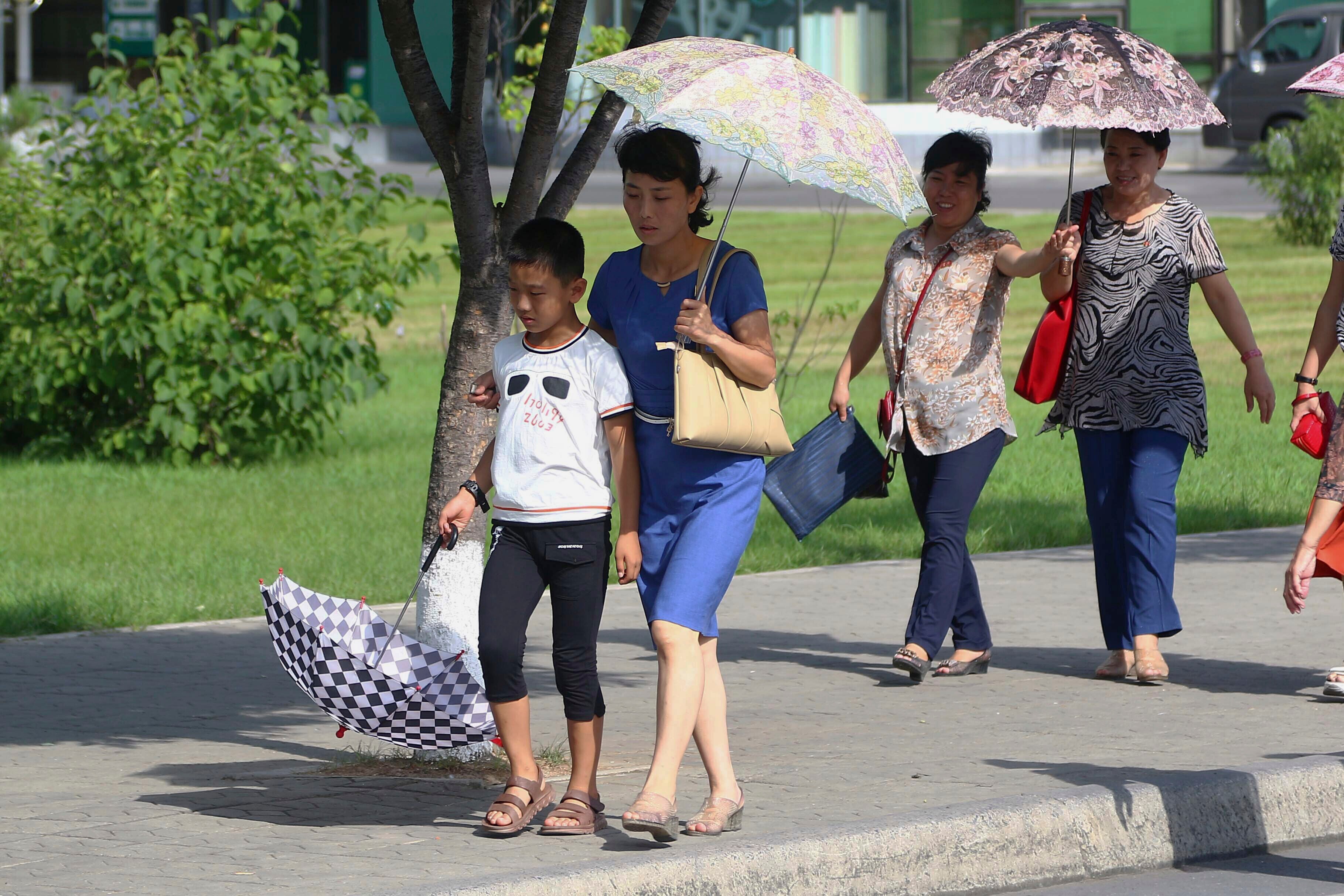 Women walk down a street holding umbrellas.