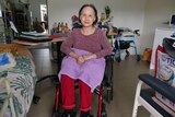 A senior woman in a wheelchair in the middle of a room. 