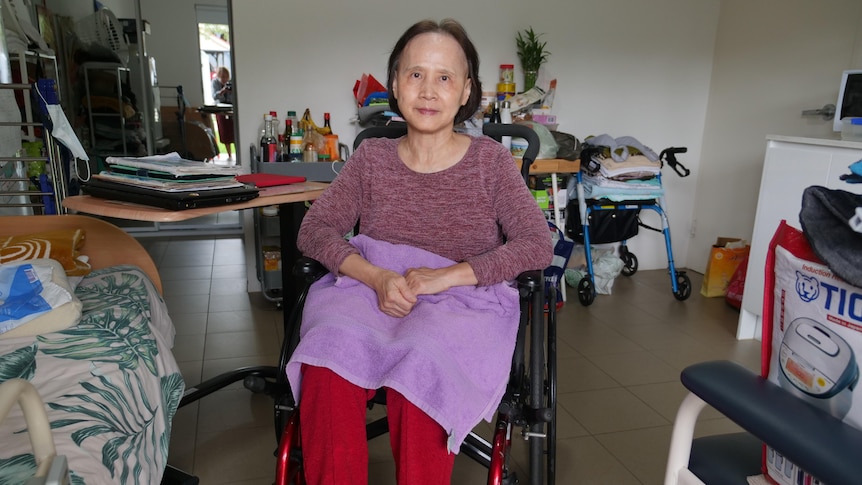 A senior woman in a wheelchair in the middle of a room. 