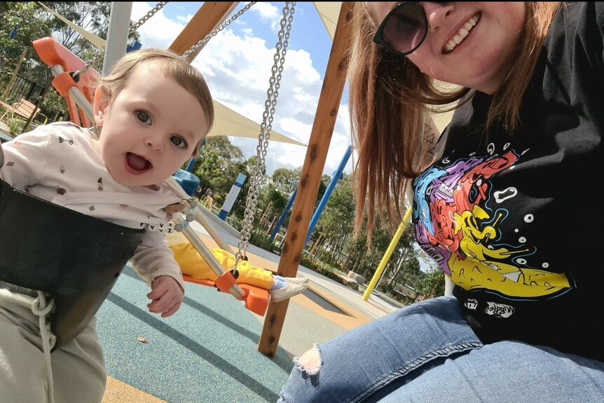 Casey de Farria with one year old Ivy in a playground wearing a Wiggles Like A Version shirt