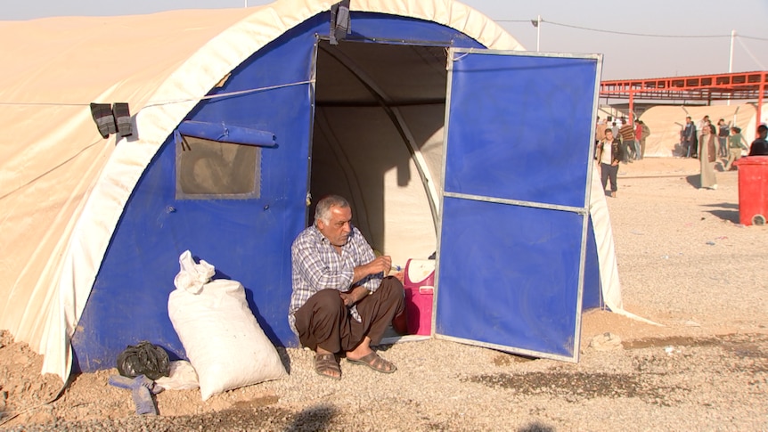 Admed Sadiq sits outside a makeshift tent in a refugee camp