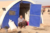 Admed Sadiq sits outside a makeshift tent in a refugee camp