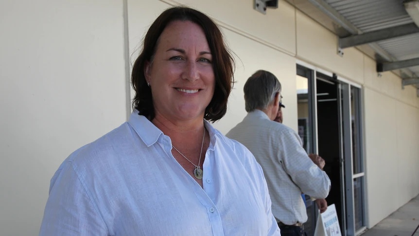 A woman smiling at the camera in a white T-shirt.