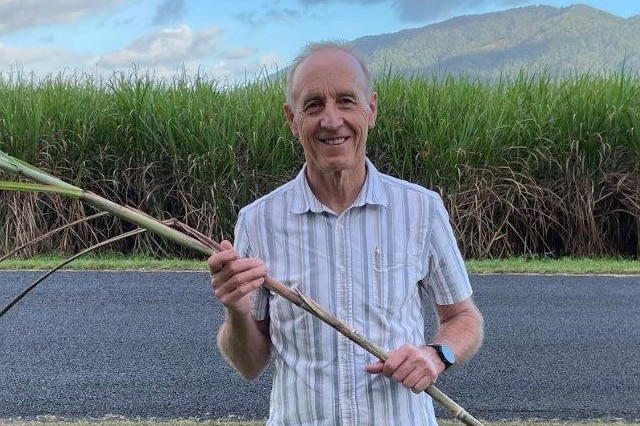 A man holding a piece of sugar cane.