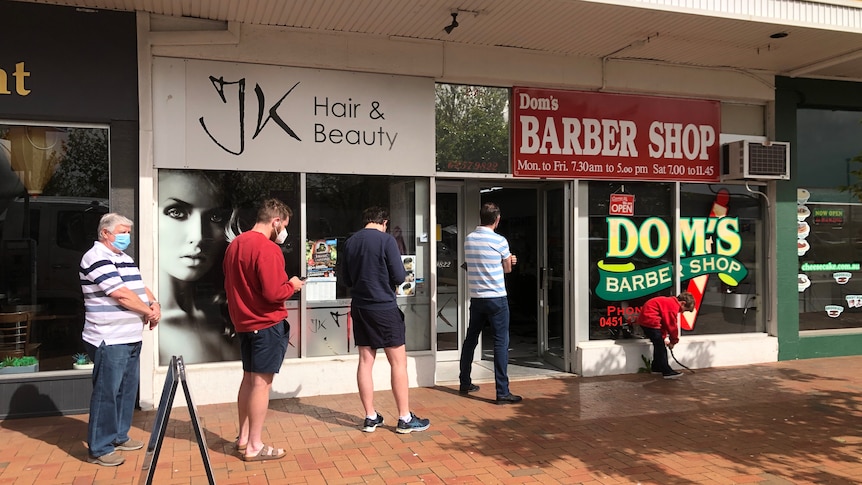 Men queue outside a barber shop