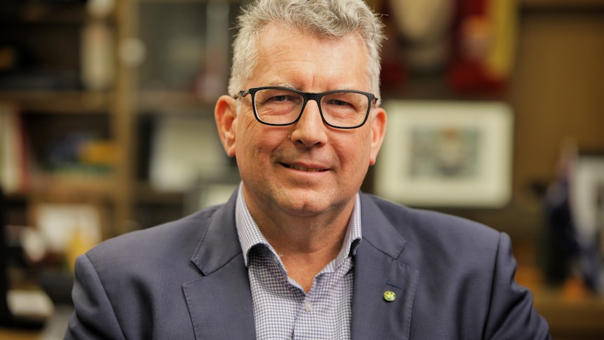 Keith Pitt wearing a blue suit and black framed glasses sitting in an office.