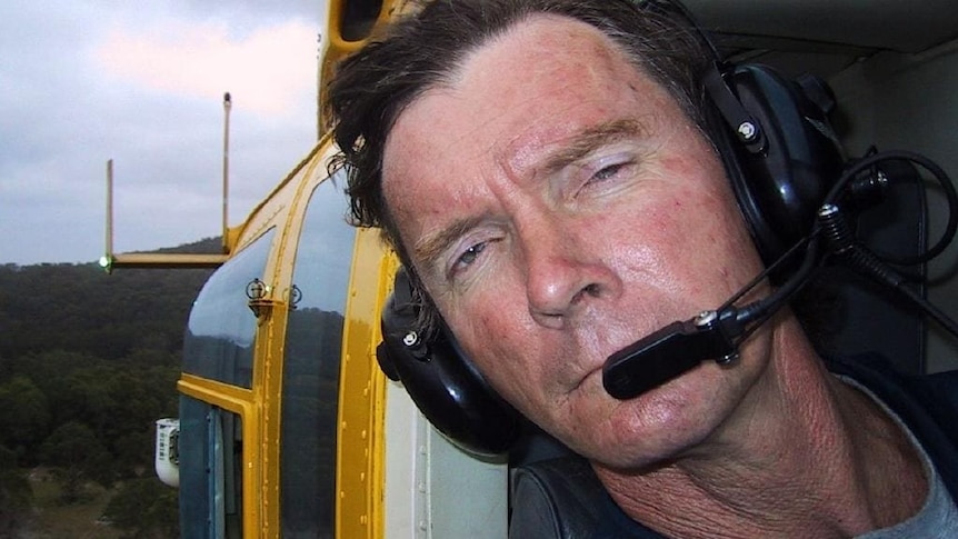 Close up of Bruce Towers leaning out of yellow helicopter window.