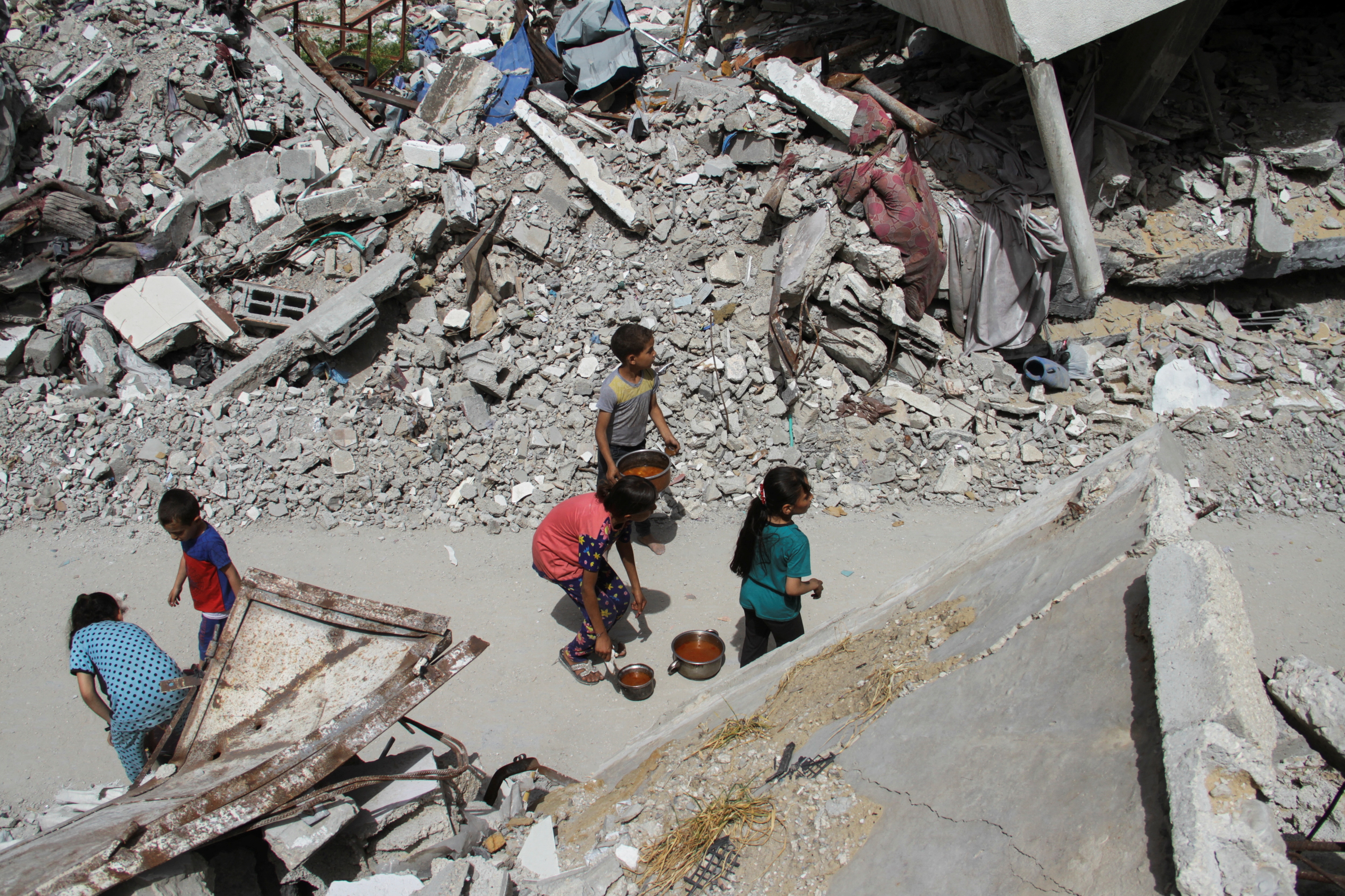 A group of children are surrounded by building rubble.
