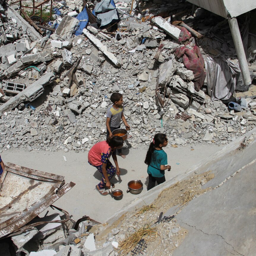A group of children are surrounded by building rubble.