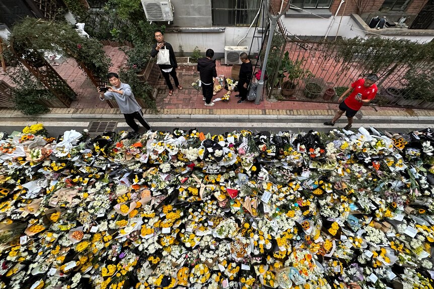 photo taken from above showing a heap of bouquets laid on road outside of building