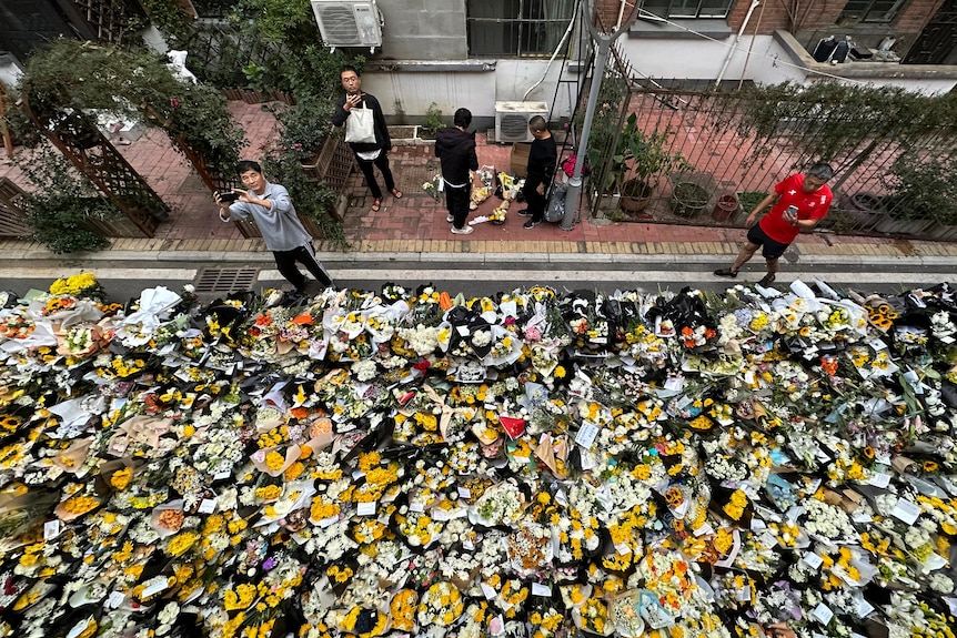 photo taken from above showing a heap of bouquets laid on road outside of building