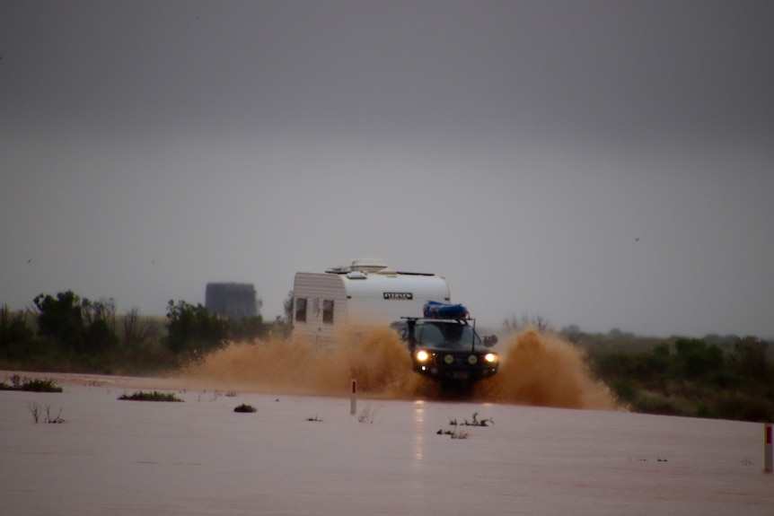 A car and a truck drive along a wet road.