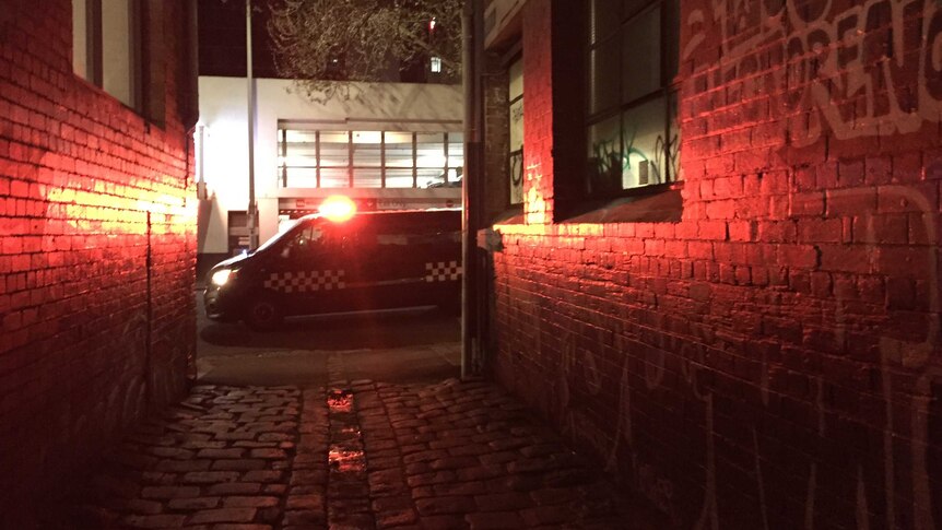 A police car drives past a Melbourne alleyway.