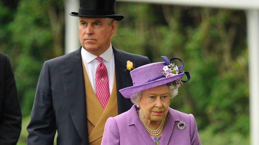 Prince Andrew, wearing a black top hat, stands behind the Queen, wearing a purple hat, at a horse racing track.