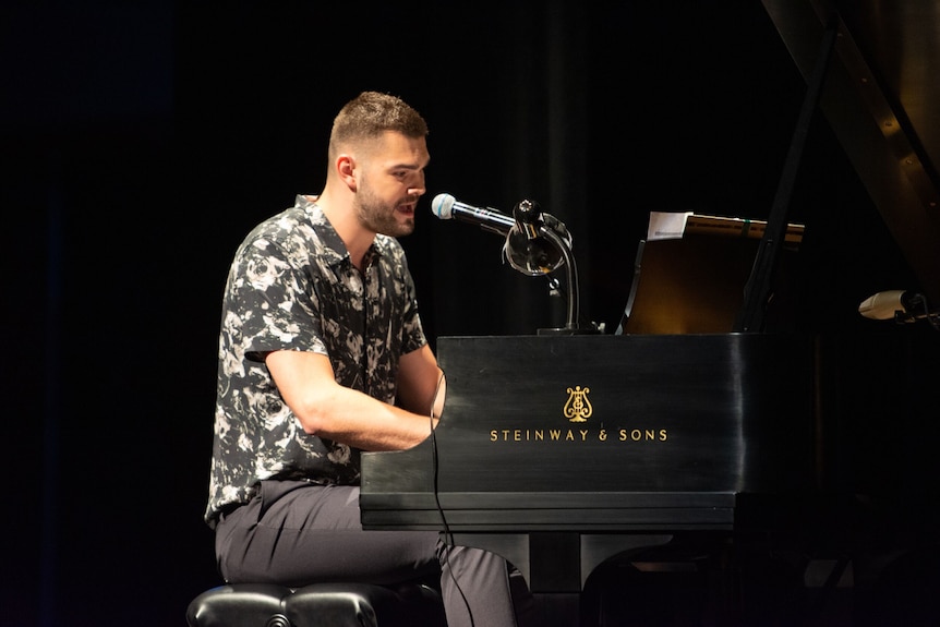A man playing the piano and singing onstage