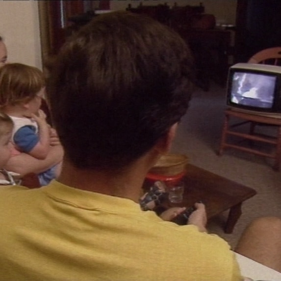 A family watching a small television in the early 1990s.
