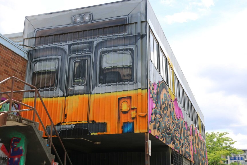 A demountable painted to look exactly like a train, with colourful yellow paint.