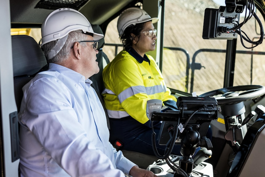 Prime Minister Scott Morrison speaking to a female truck driver in the cab of a mining haul truck. 
