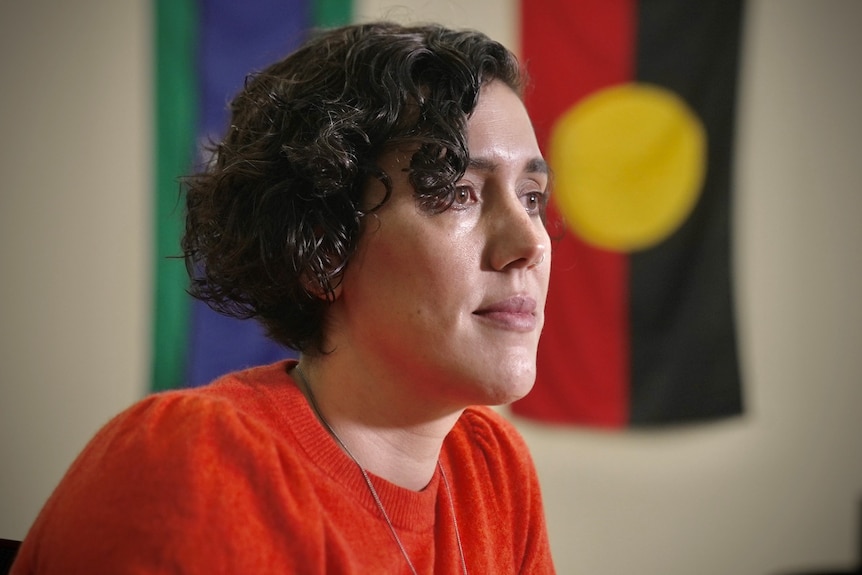 A woman wears a red shirt sitting in a room.