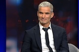 Former Socceroo Craig Foster wears a black suit and tie on Q+A.