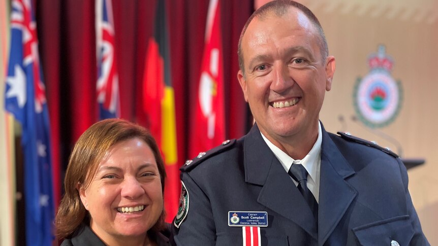A man in his firefighter's uniform at a bravery awards ceremony with his wife
