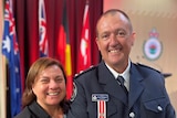 A man in his firefighter's uniform at a bravery awards ceremony with his wife