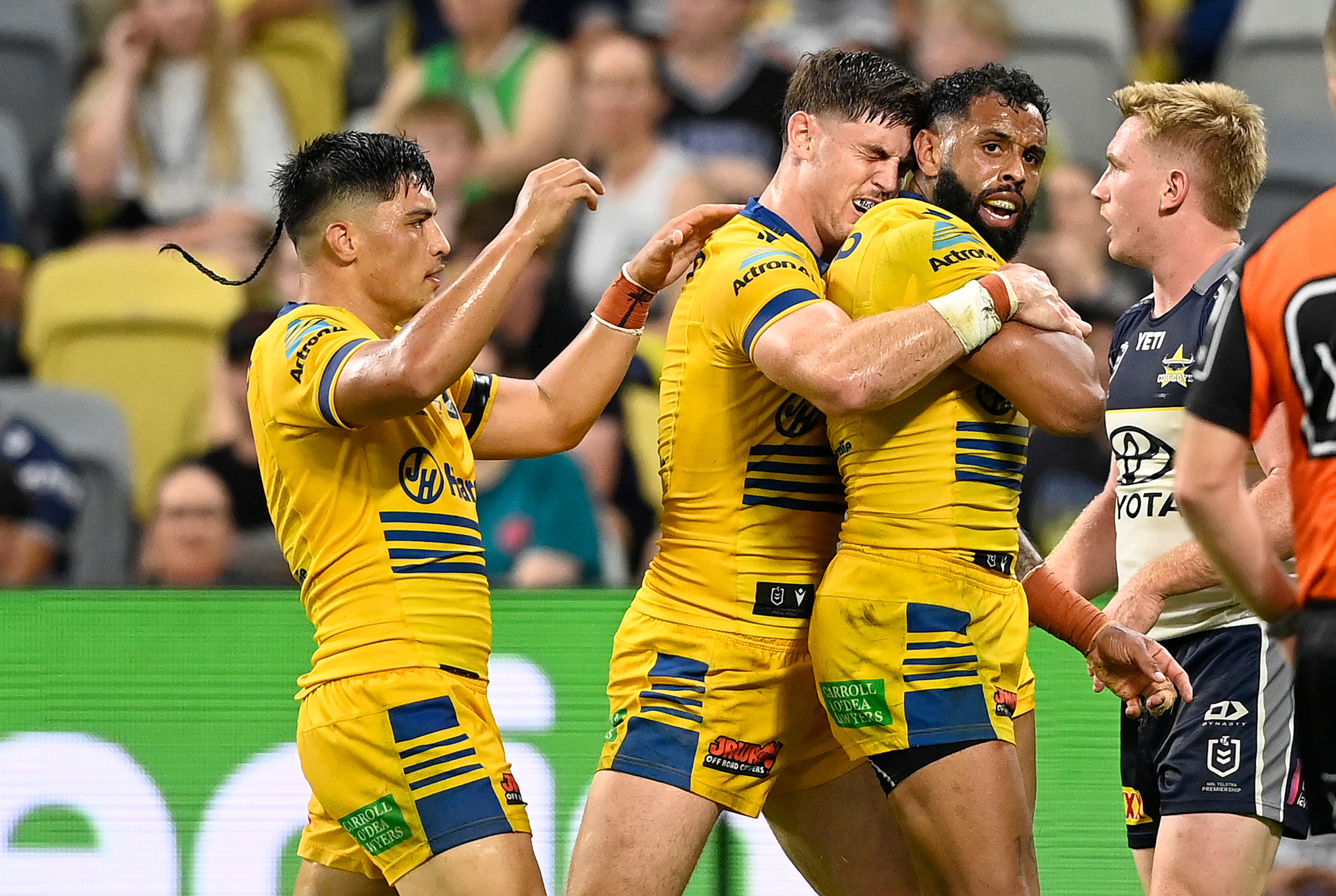 A group of rugby league players in yellow celebrate a try.