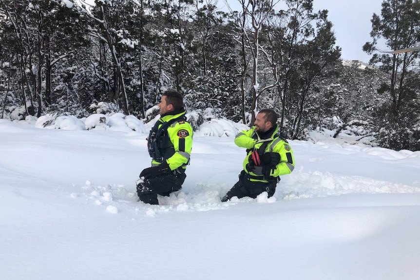 Two police officers walking through deep snow