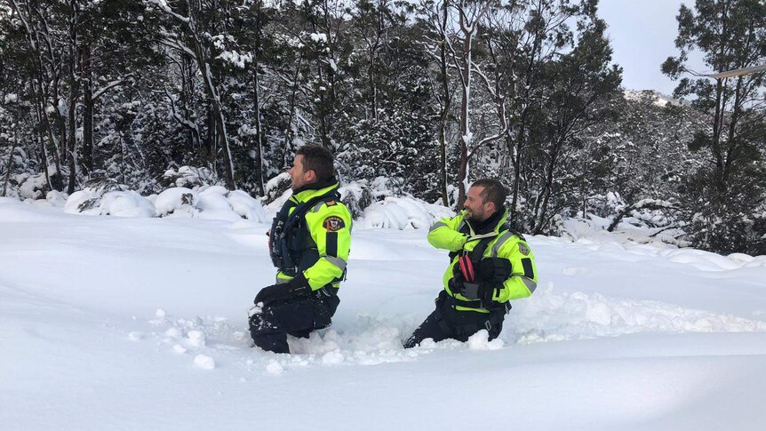 Two police officers walking through deep snow