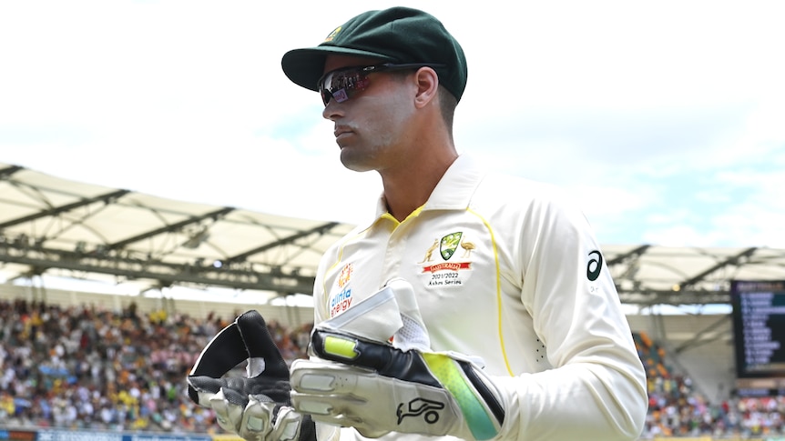 An Australian wicketkeeper wearing his gloves at the Gabba during the first men's Ashes Test.