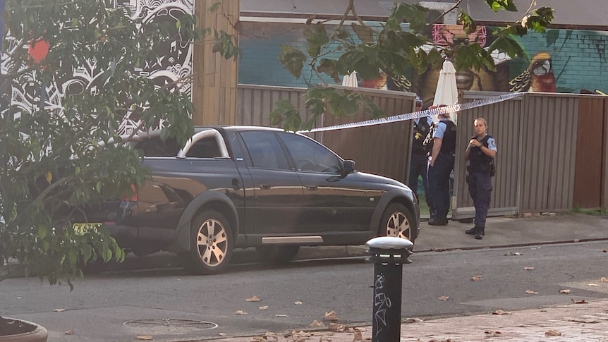 Police officers stand near the entrance of a cafe.