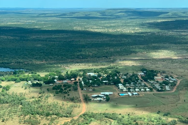 an aerial photo of a small town surrounded by green bushland