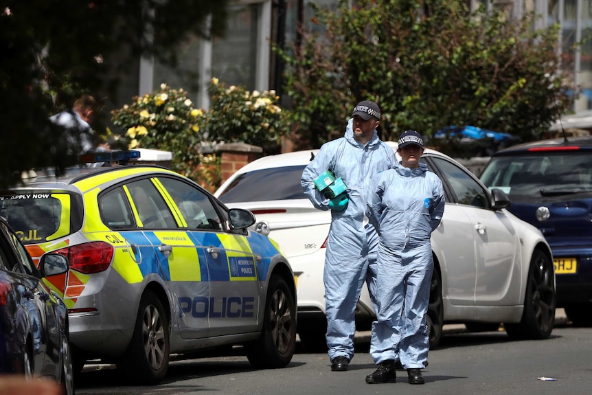 Police officers standing on a road next to a police car