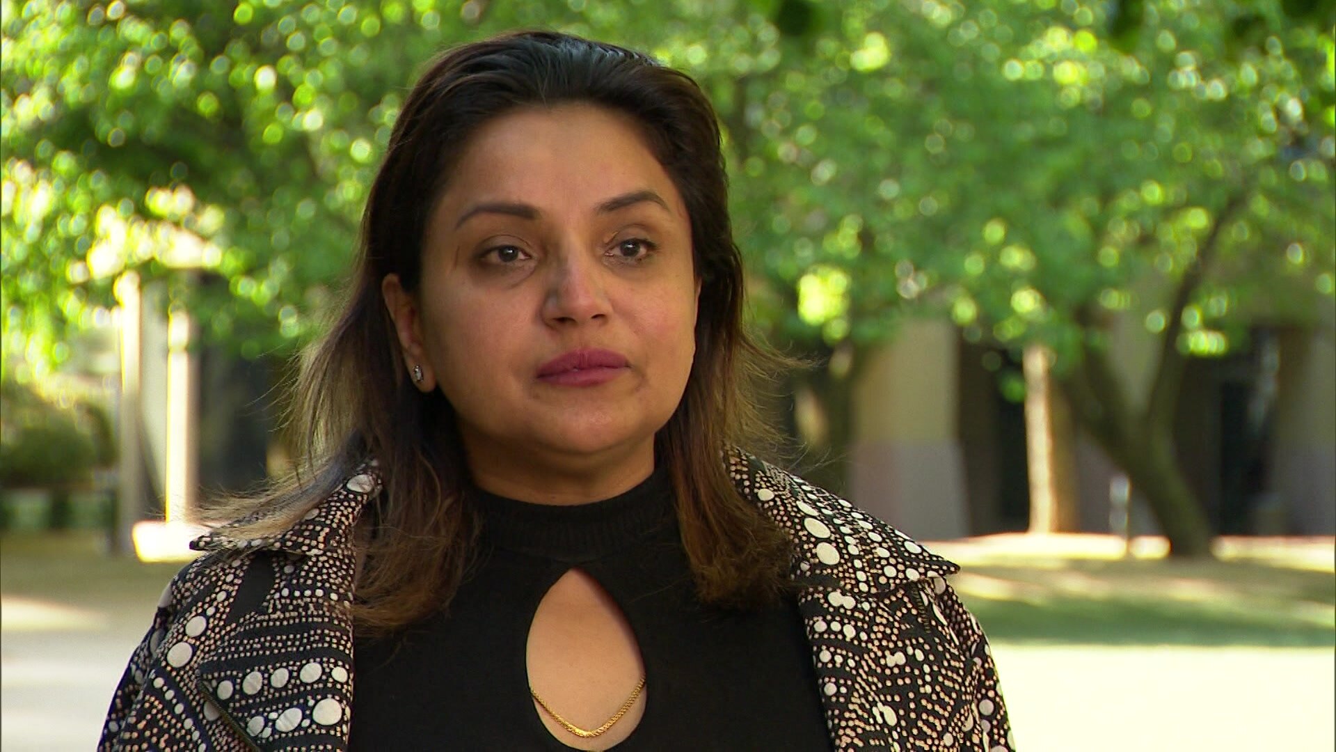 A woman with trees in the background.