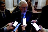 Reporters illuminate Mitch McConnell's face as they point their smartphones towards his face