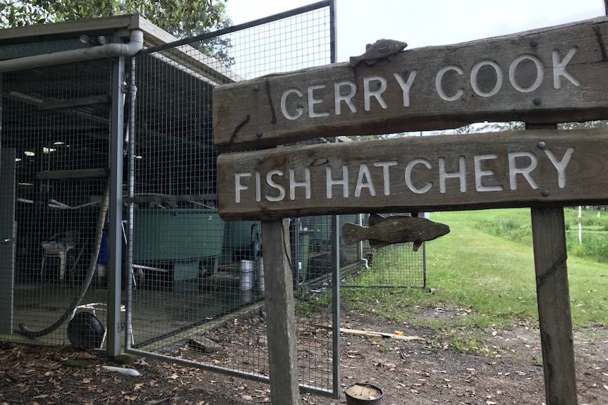 The sign outside the fish hatchery with the shed, tank and pond in the background.