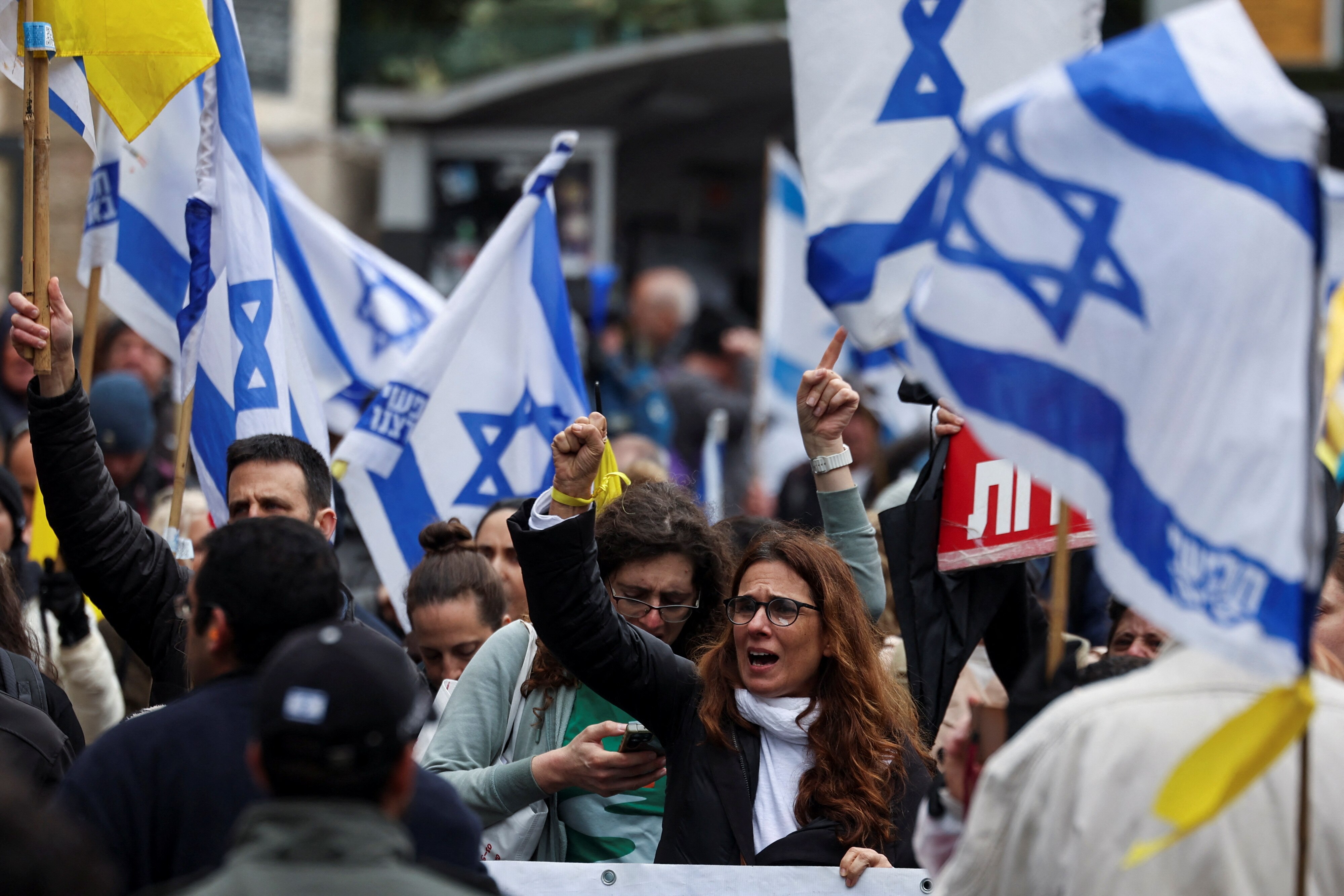 People protesting in the streets of Jerusalem holding Israeli flags.