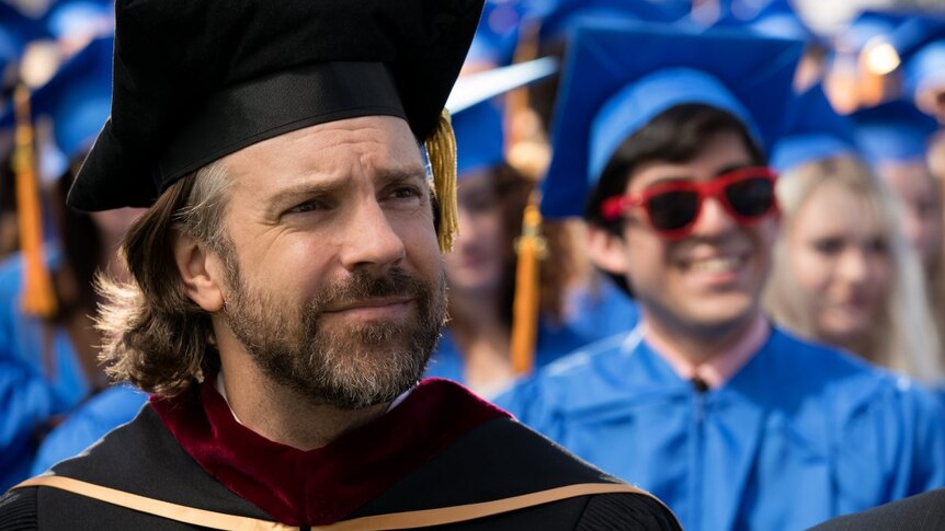 Colour close-up still of Jason Sudeikis wearing graduation gown in 2019 film Booksmart.