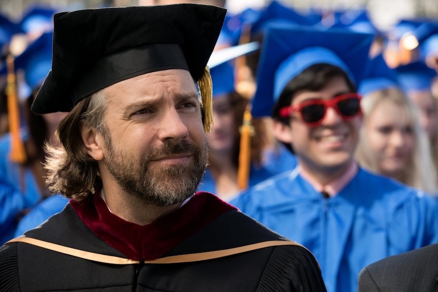 Colour close-up still of Jason Sudeikis wearing graduation gown in 2019 film Booksmart.