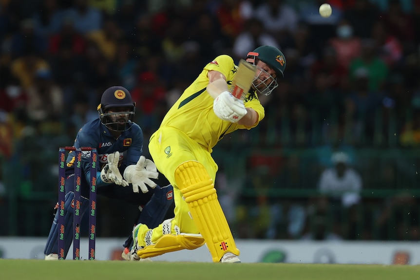 Australian batsman Travis Head lofts the ball down the ground during an ODI as the wicketkeeper watches.