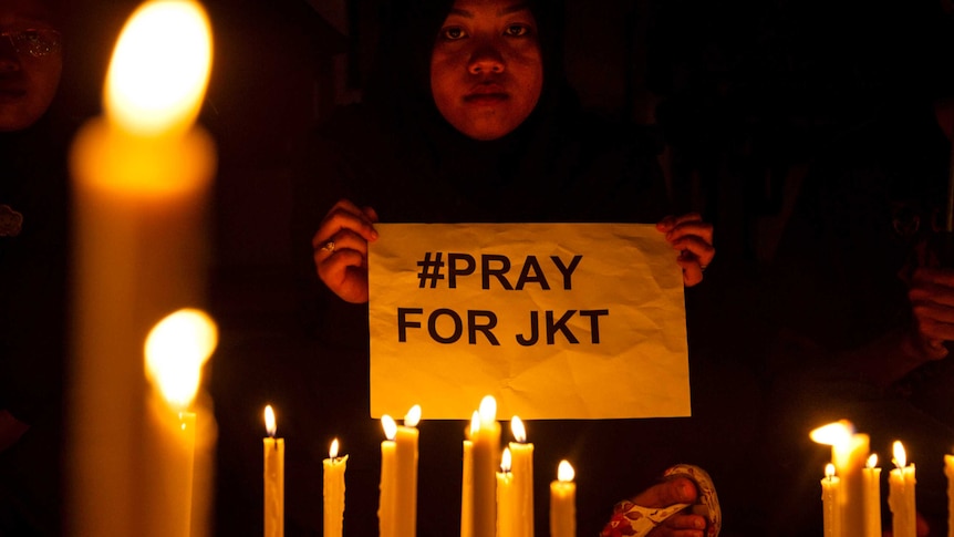 Indonesian Muslim woman holds pray for Jakarta placard.