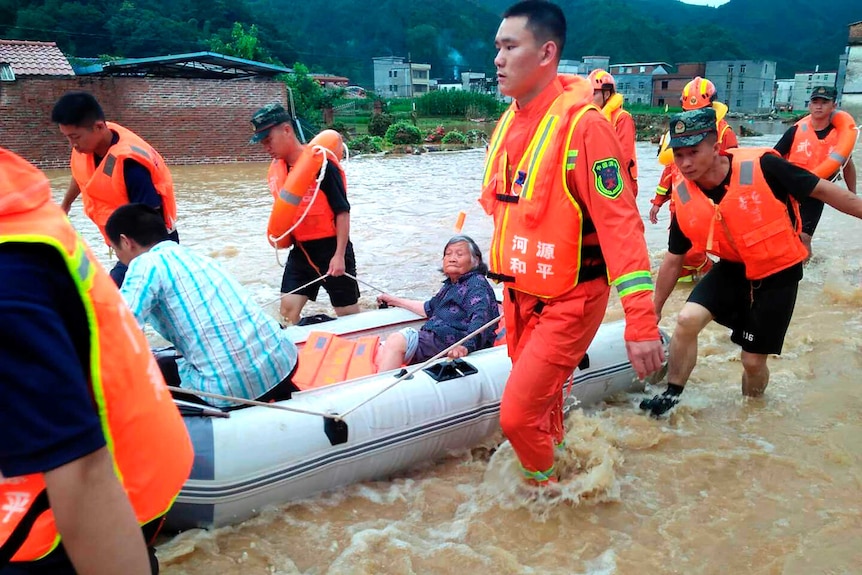 rescuers evacuate an elderly woman on a boat over a body of water