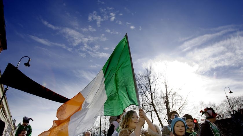 A young girl carries the Irish flag, with a wintry sky in the background