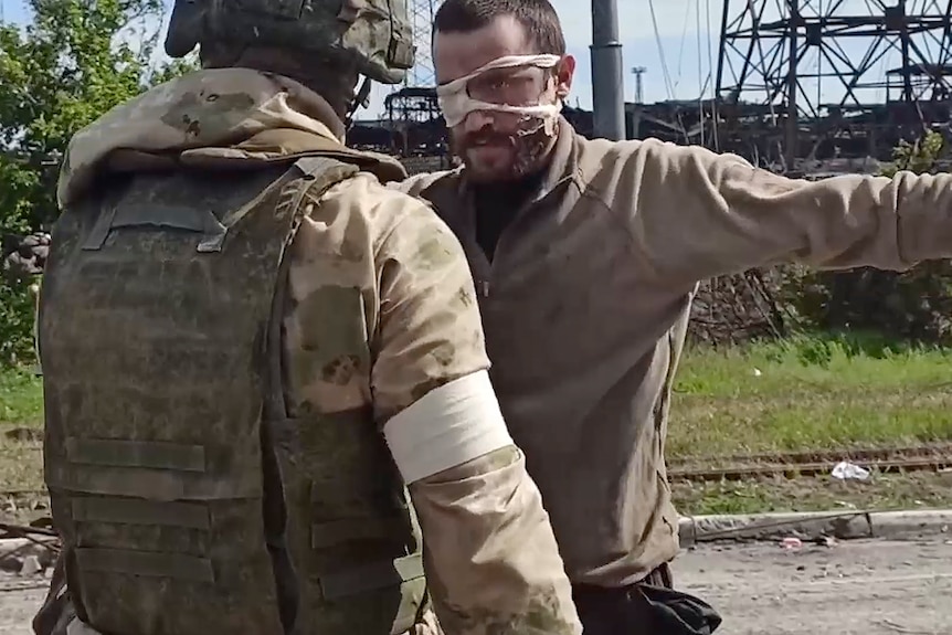 Un soldat rus inspectează un soldat ucrainean care poartă un plasture pe ochi.